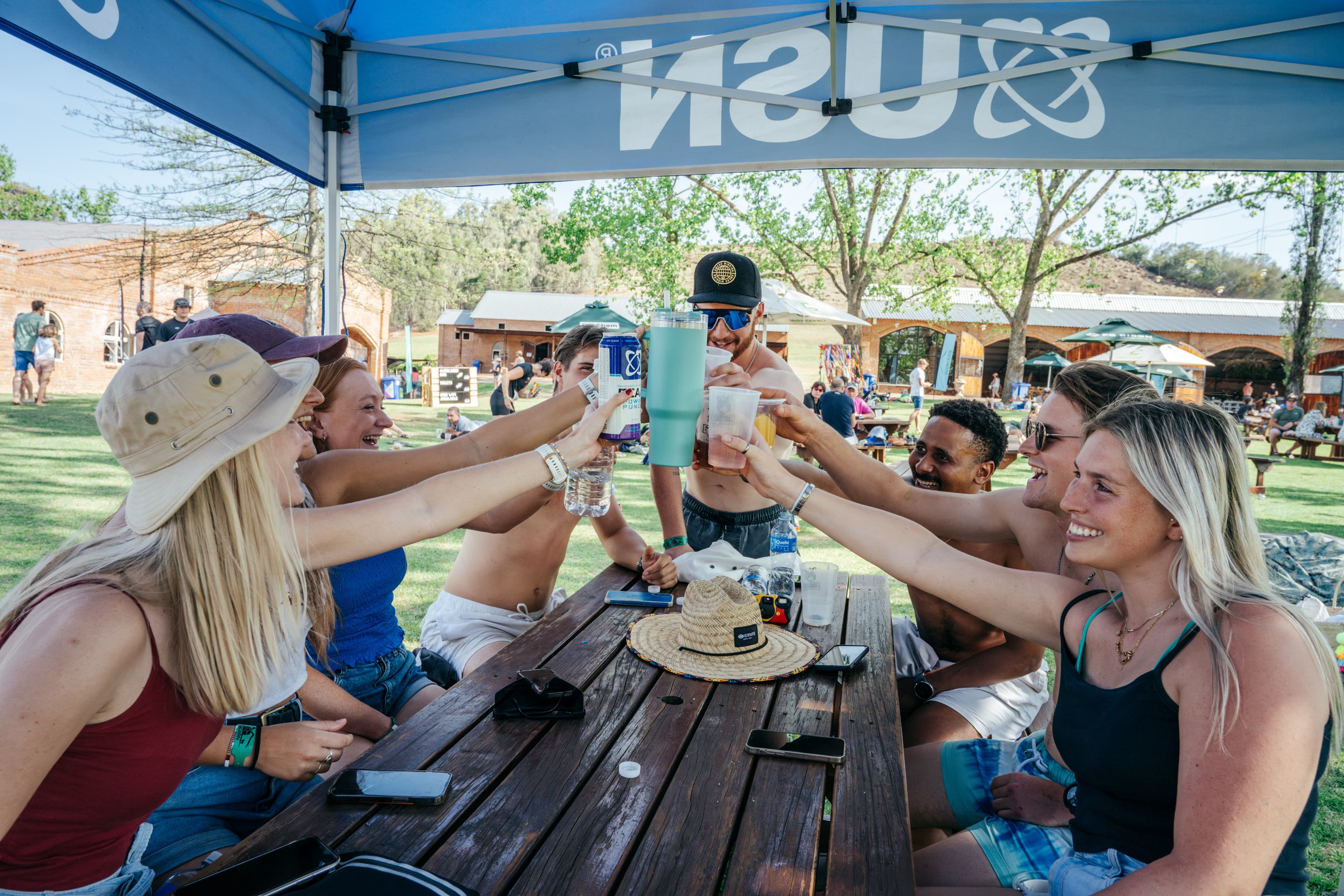 Friends cheering with drinks at race village