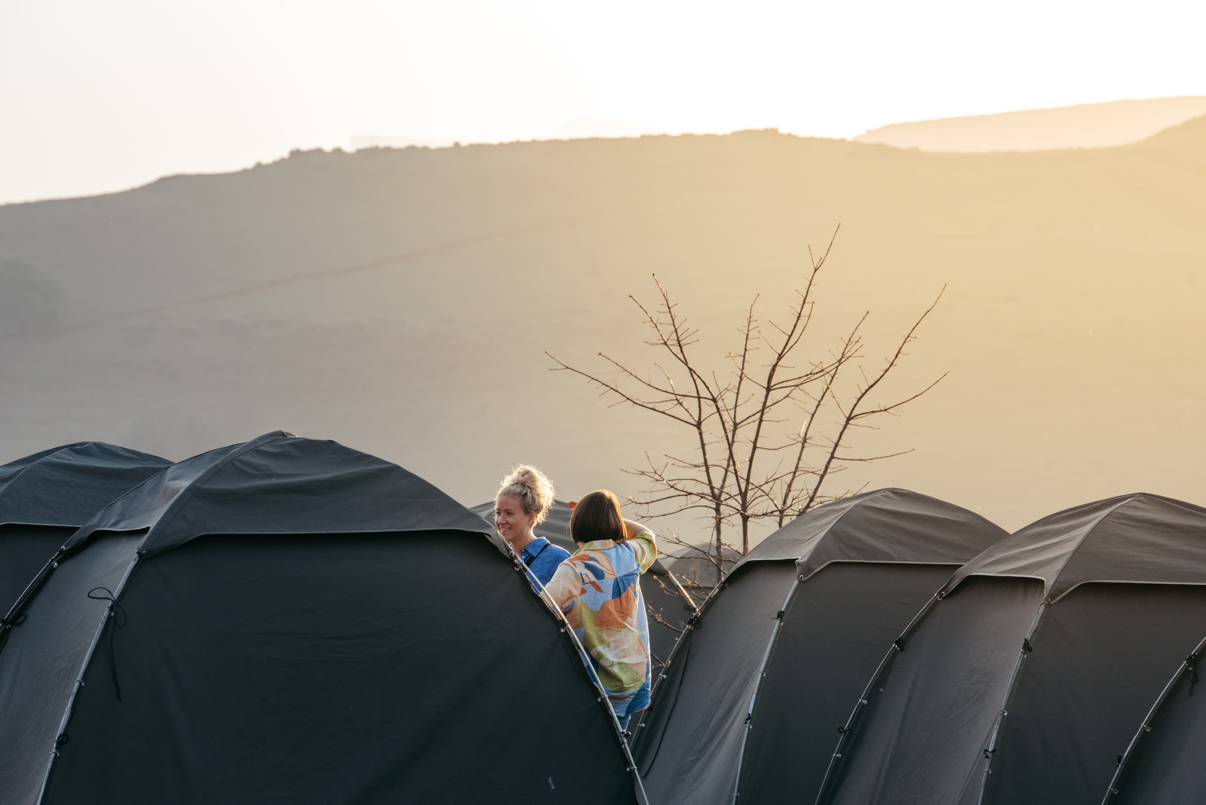 Riders chatting between tents at sunset