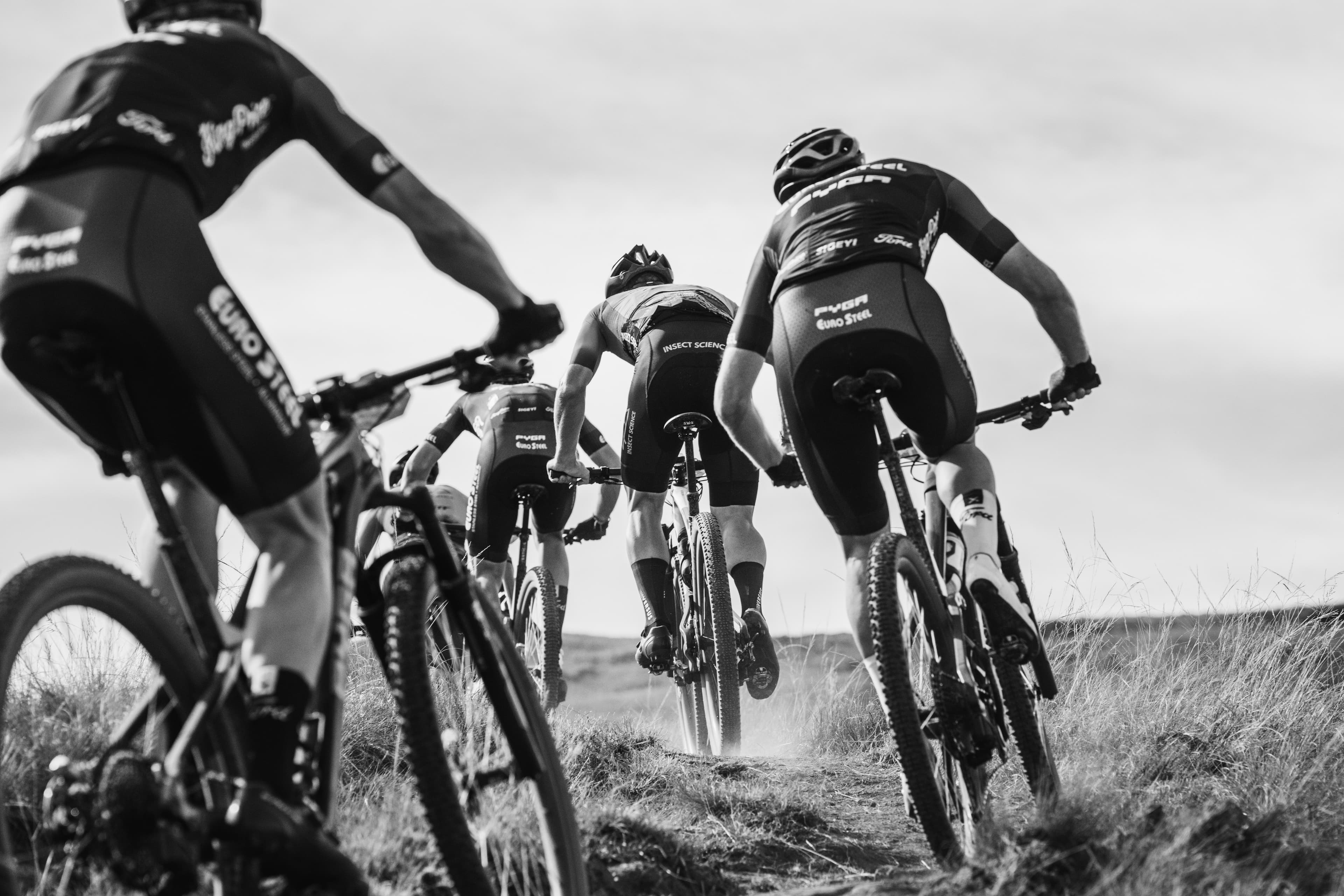 Riders climbing trail in black and white