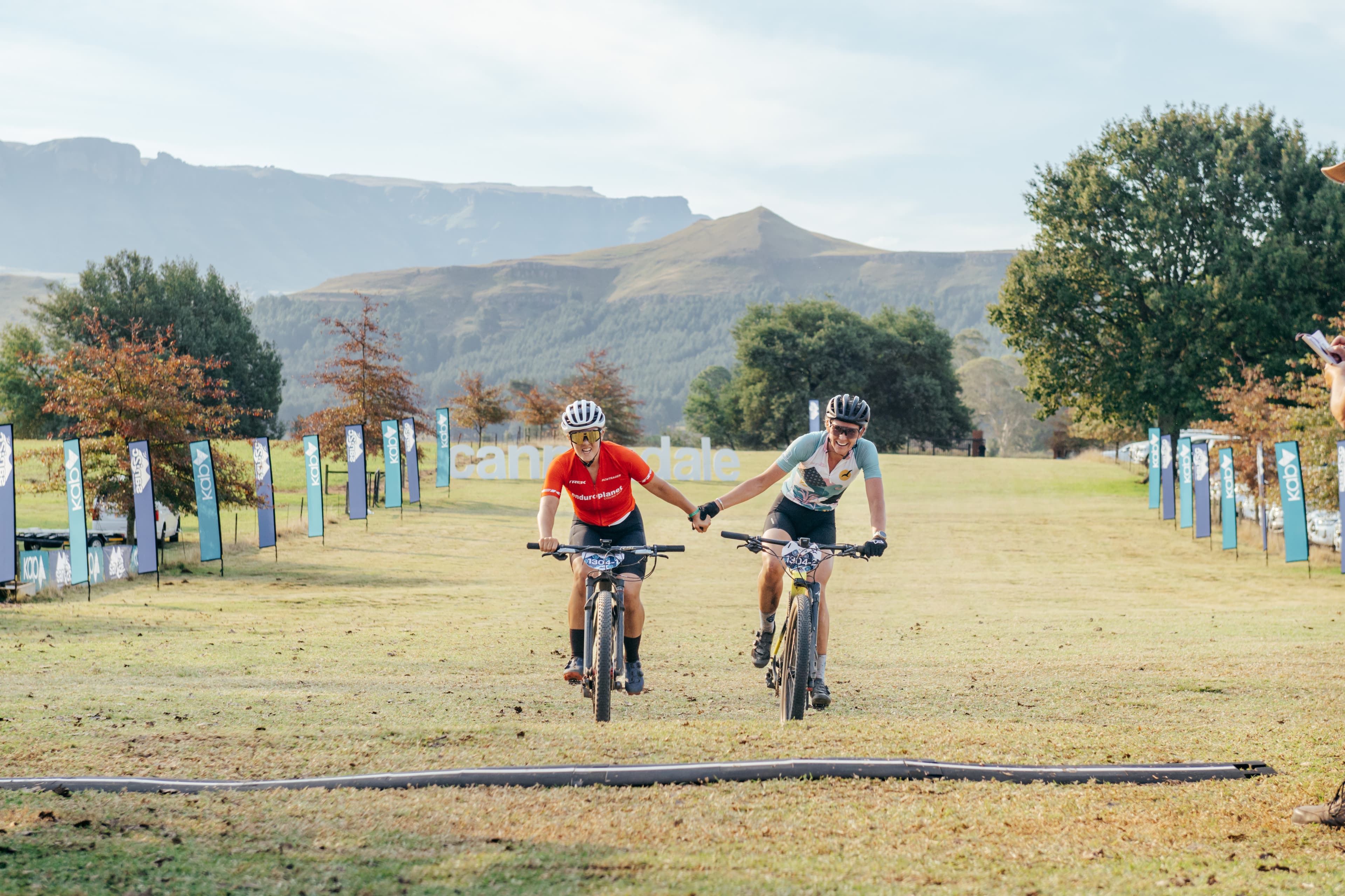 Riders crossing finish line holding hands